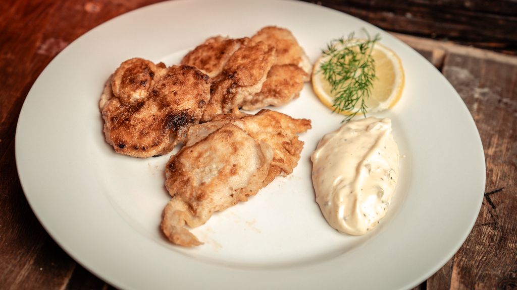 Ein tallerken med sprøsteikte torsketunger, remulade og ei sitronskive. Foto.
