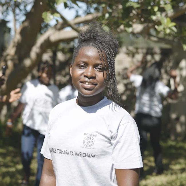 Portrett av ung jente i hvit t-skjorte med logo. Foto.