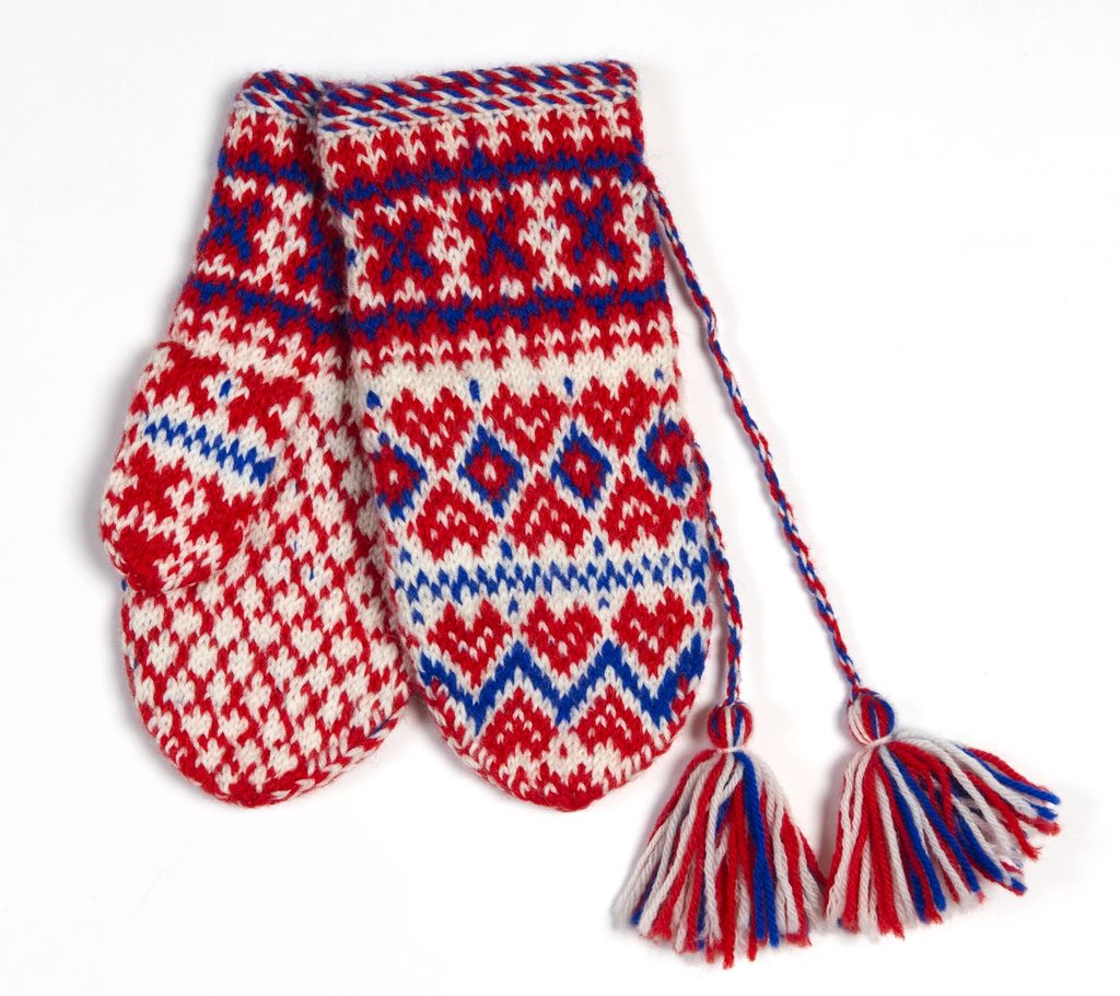 Strikkavottar med duskar og mønster i raudt, kvitt og blått. Foto.