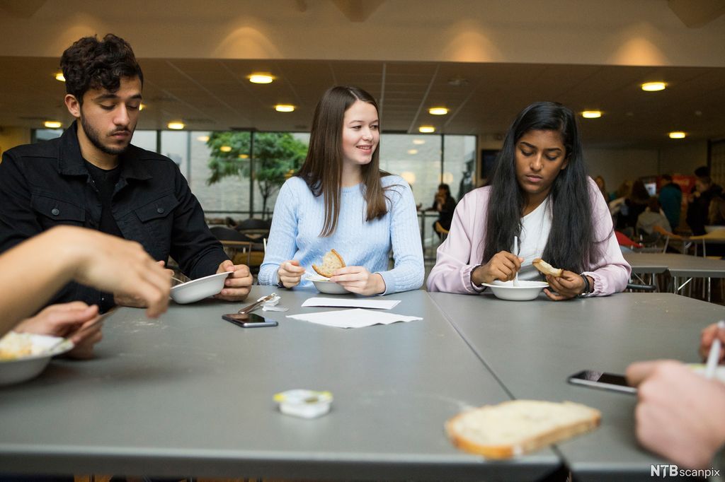 Ungdommar et i lag i ei kantine. Foto. 
