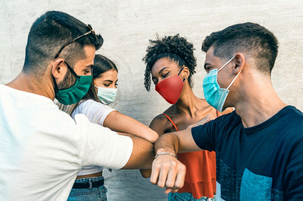 En gruppe ungdommer med munnbind hilser med albuen. Foto.