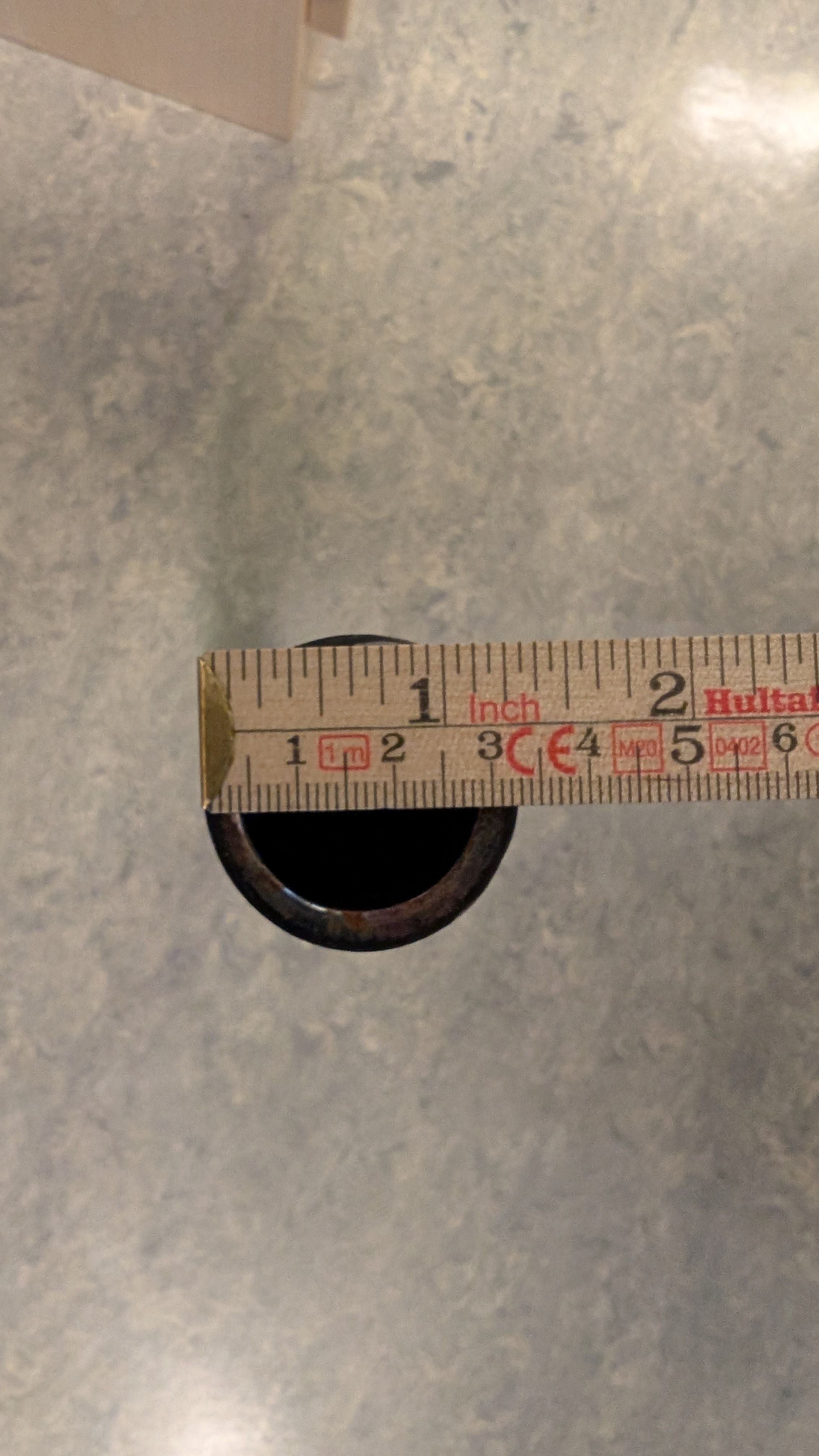 En meterstokk måler den ytre diameteren på et stålrør til 3,3 centimeter. Foto.