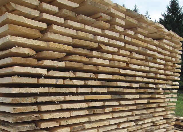 Stabel med grov trelast som ligger til tørk. Foto.