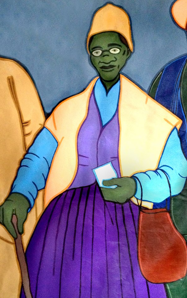 Painting: We see an older black woman with glasses, wearing a hat. Bright colours are used. The drawing is simple. 