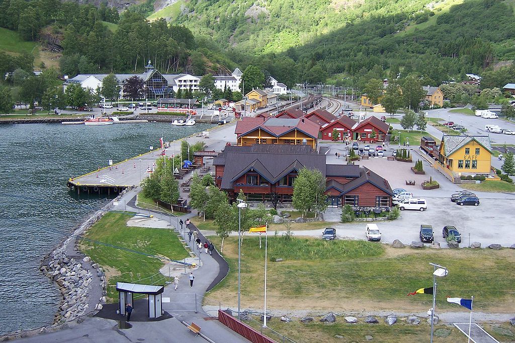 Flåm, ei bygd inst i Aurlandsfjorden. På biletet ser vi turistkaia med busetnad og parkeringsplassar, og Fretheim Hotel og Flåm jernbanestasjon i bakgrunnen. Foto.