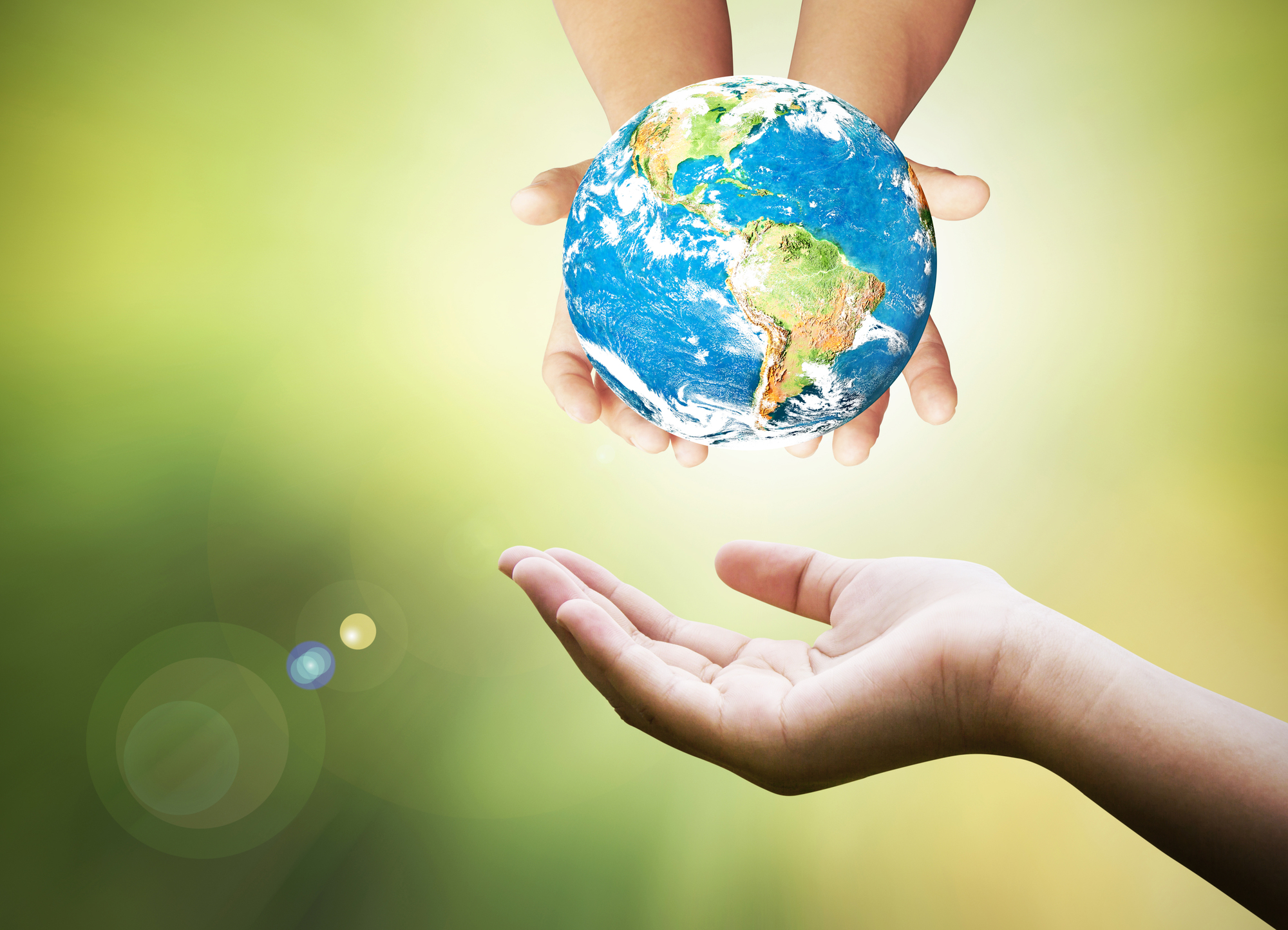 Childrens hands holding a globe above an adult hand. Photo.