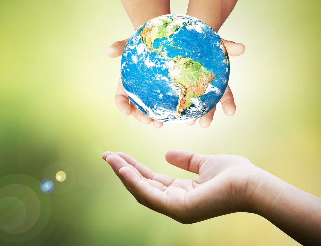 Childrens hands holding a globe above an adult hand. Photo.