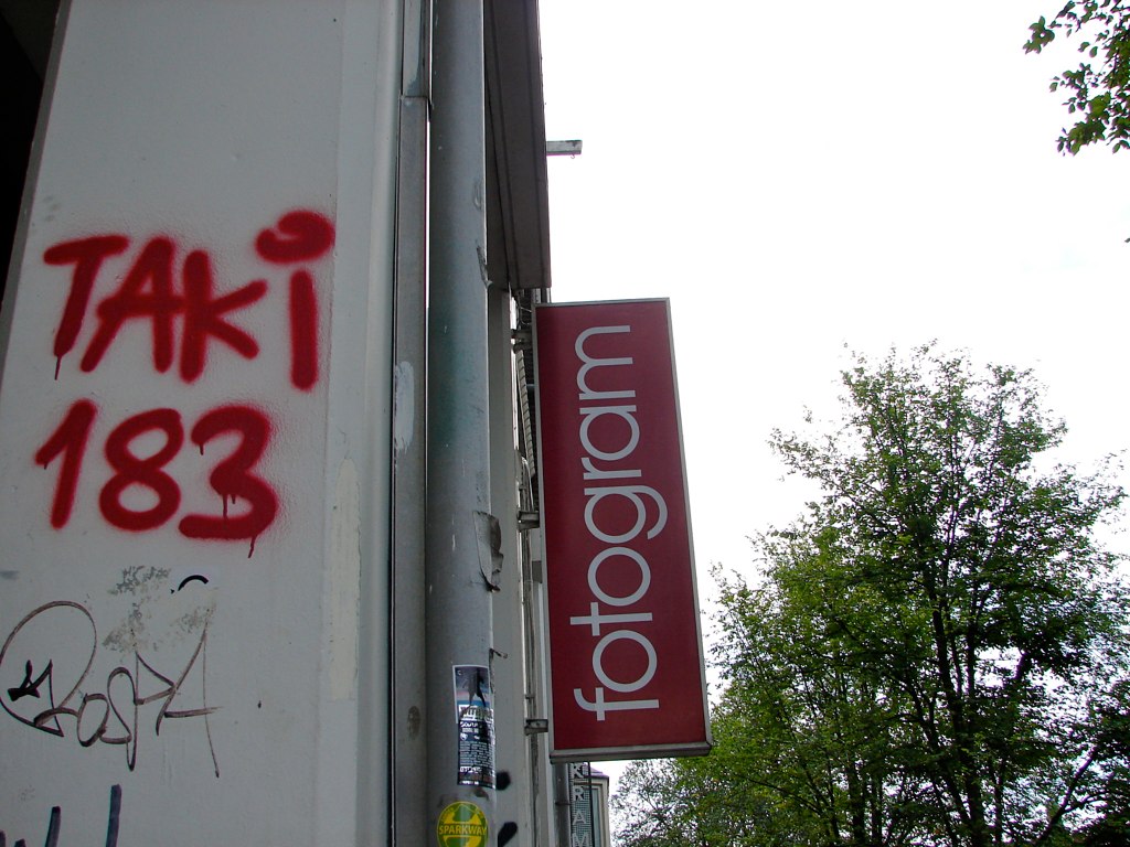 En murvegg med "TAKI 183" i rød graffitiskrift. Foto.