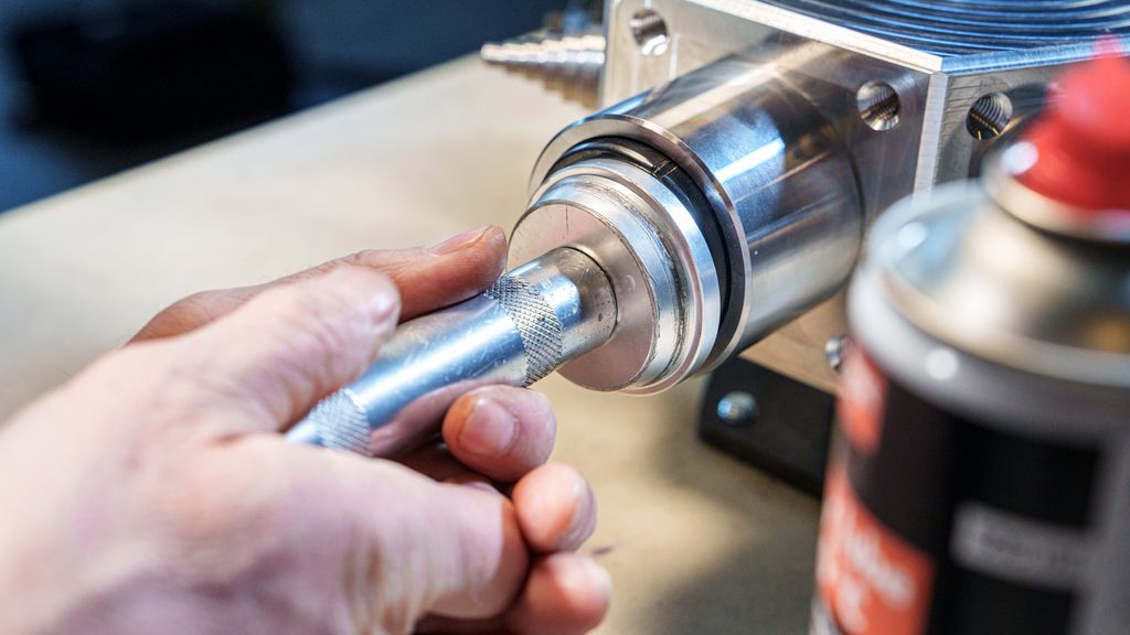 To hender som presser et verktøy mot en svart gummiring. Foto.