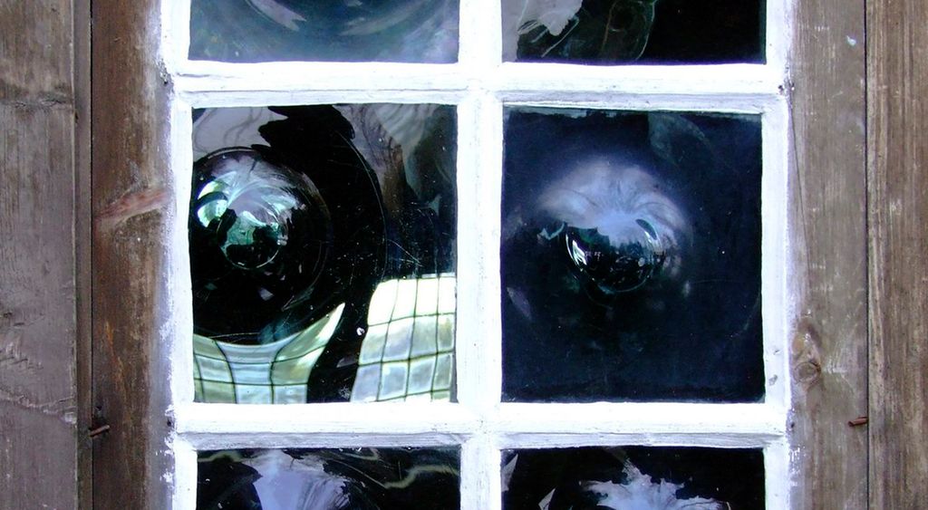 Gammalt vindauge med veldig ujamt glas. Foto.