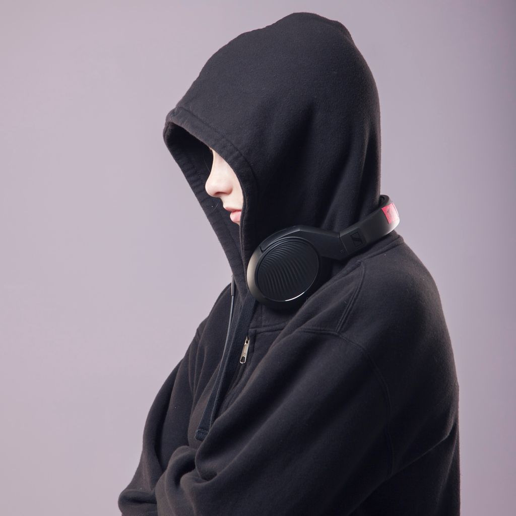 Person in a black hoodie with a headset around their neck. Photo.