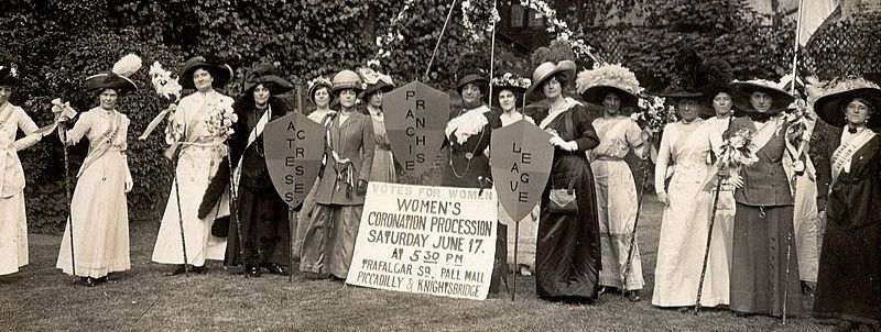A photo taken at the end of the nineteenth century showing 16 middle/upper-class women dresses in the traditional dresses of the time. They are demonstrating for women's right to vote.