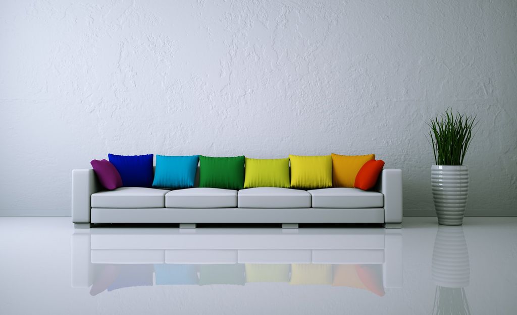 Hvit sofa med fargerike puter. Foto.