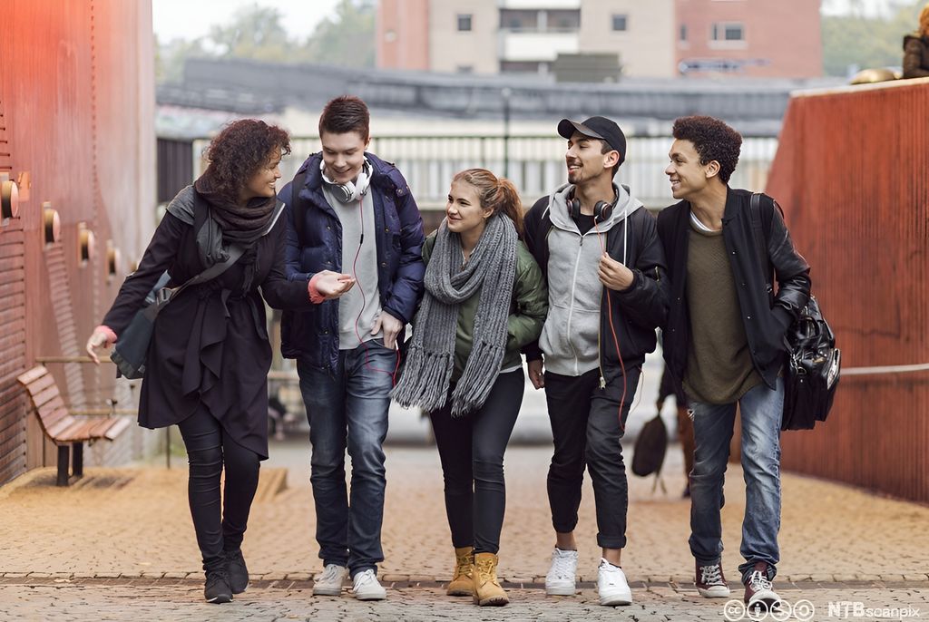 Ungdommer går langs ei gate og snakker sammen. Foto.