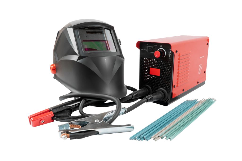 Sveiseapparat med ledninger, sveisepinner og sveisemaske på hvit bakgrunn. Foto.