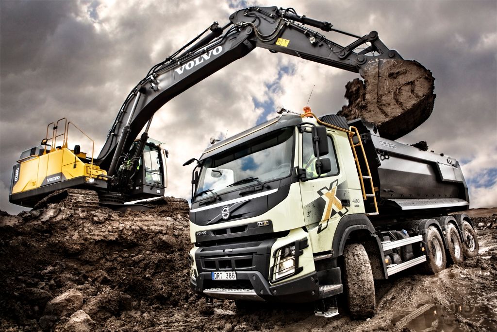 Bildet viser en lastebil som blir lastet av en gravemaskin.