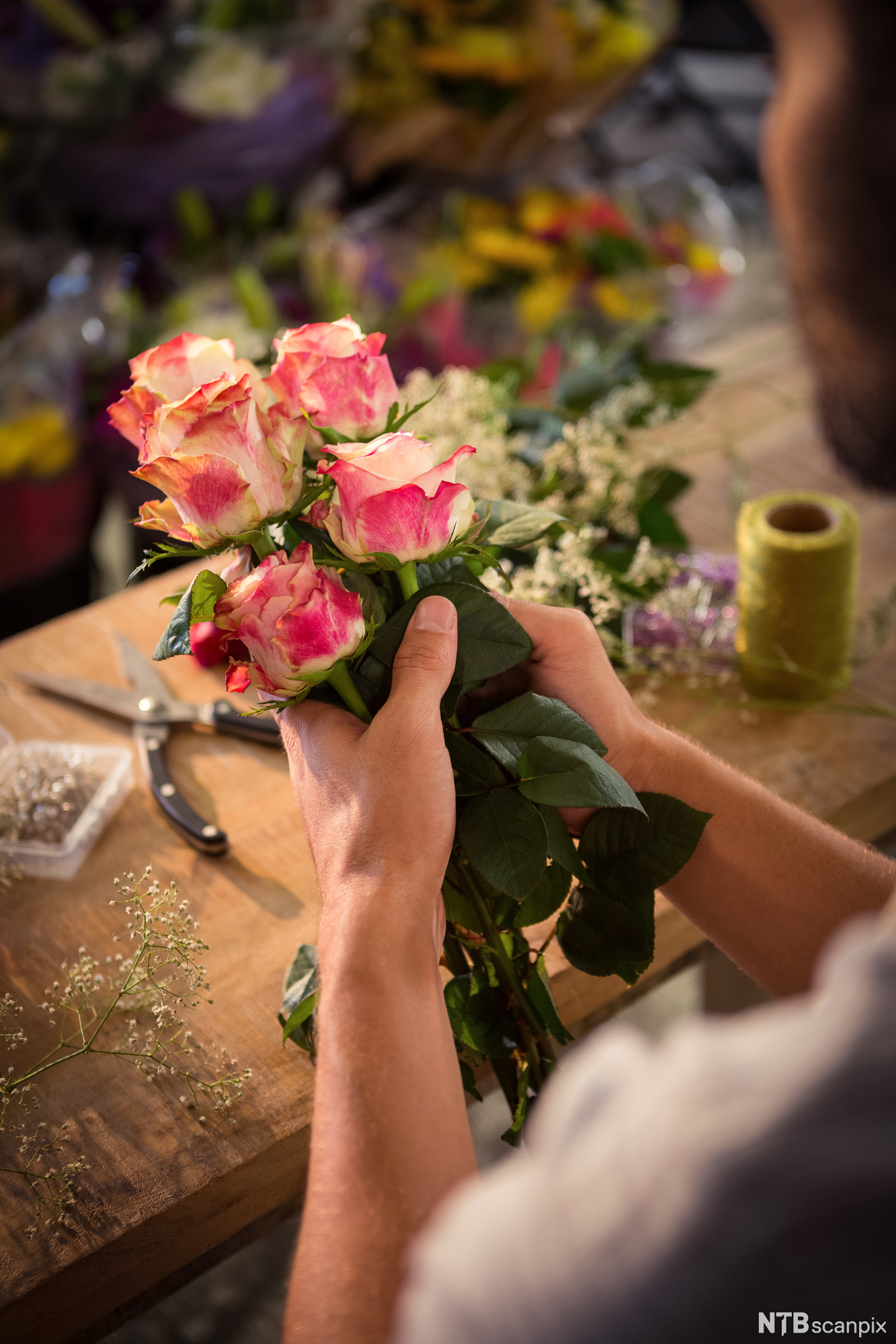 Hender som setter sammen en blomsterbukett. Foto.