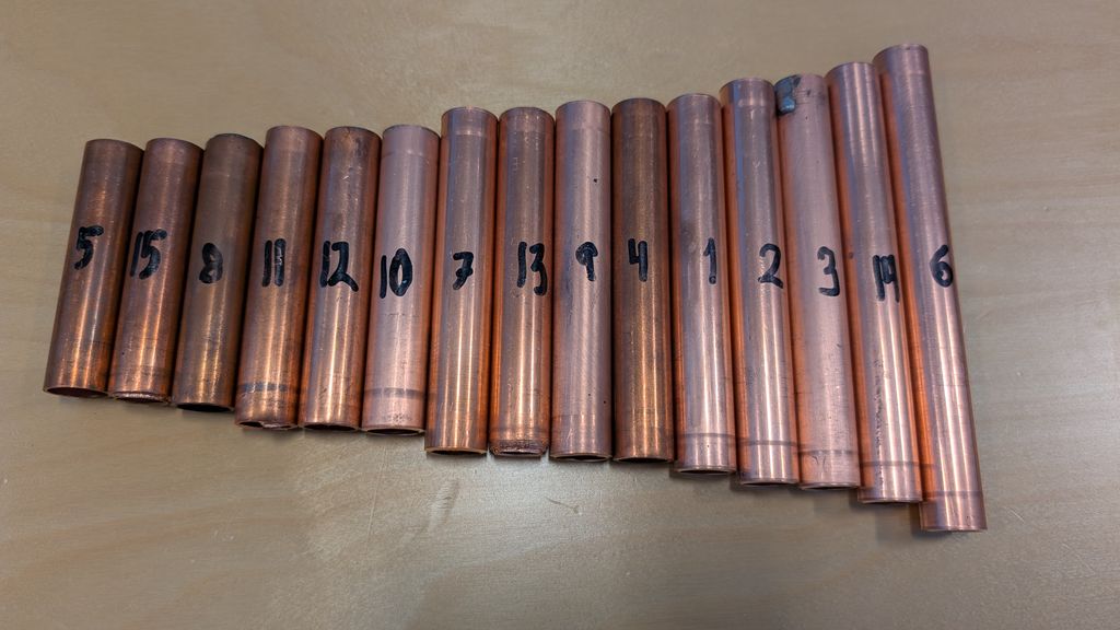 15 nummererte stubbar av koparrøyr ligg ved sida av kvarandre sorterte etter storleik. Nummereringa er ikkje i rekkefølge. Foto.