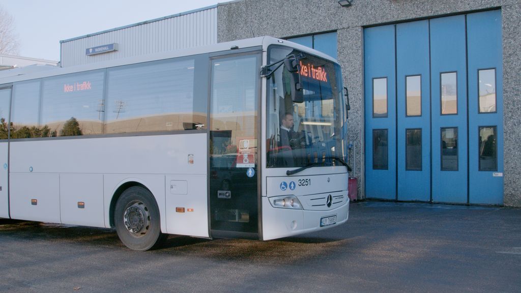 Bussjåfør som sitter i en hvit buss. Foto.