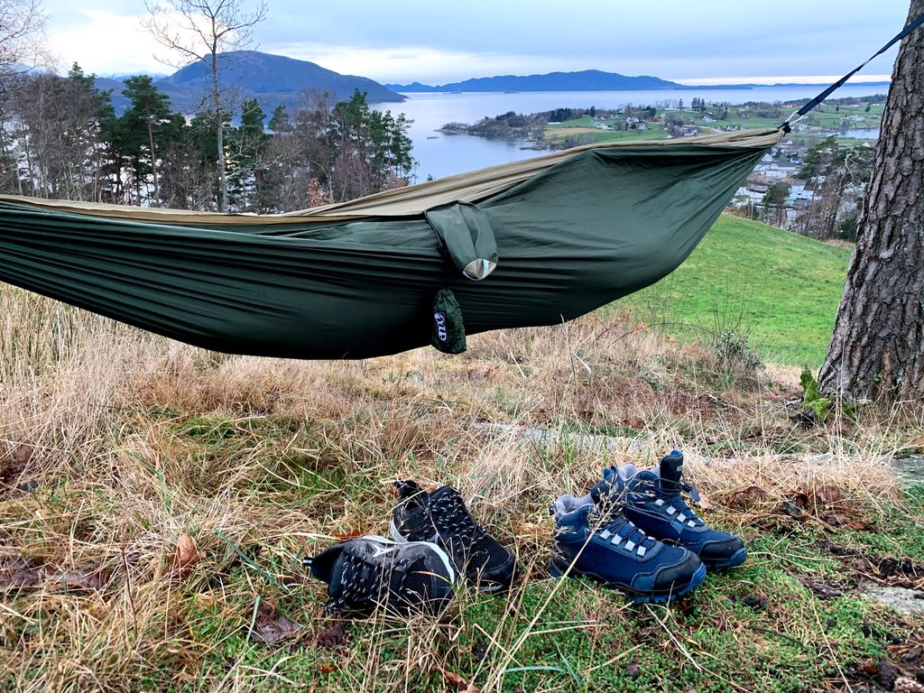 Ei hengekøye og to par sko med utsikt over fjorden. Foto.
