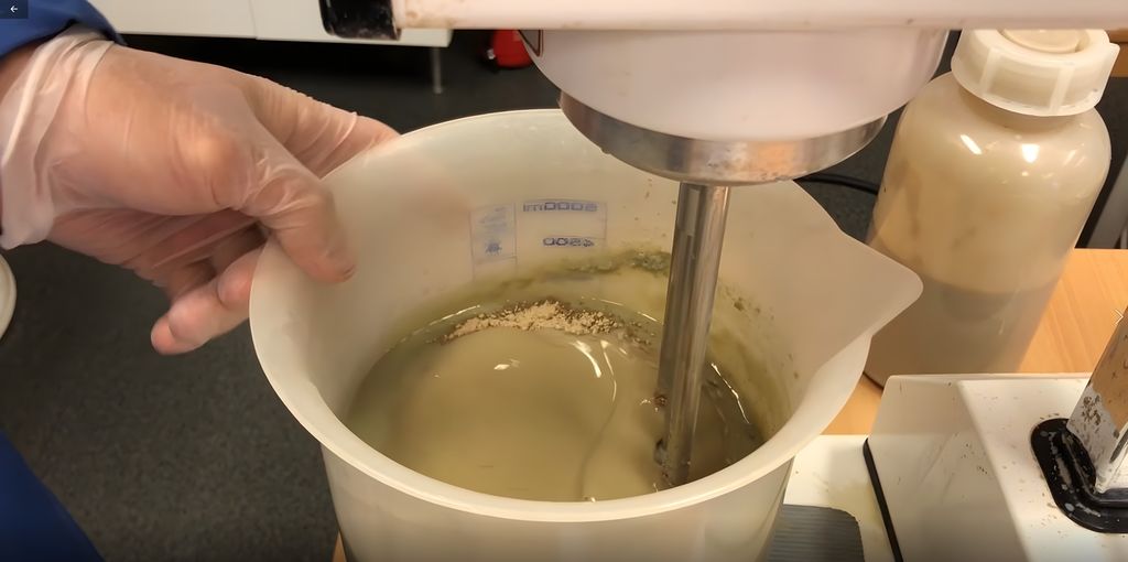En mikser rører sammen pulver og væske til boreslam i en plastbolle i laboratoriet. Foto.