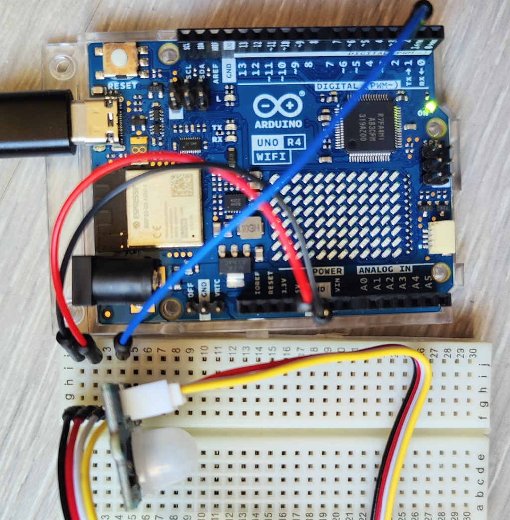 Mikrokontroller og sensor kopla sammen med ledninger via et koblingsbrett. Foto.