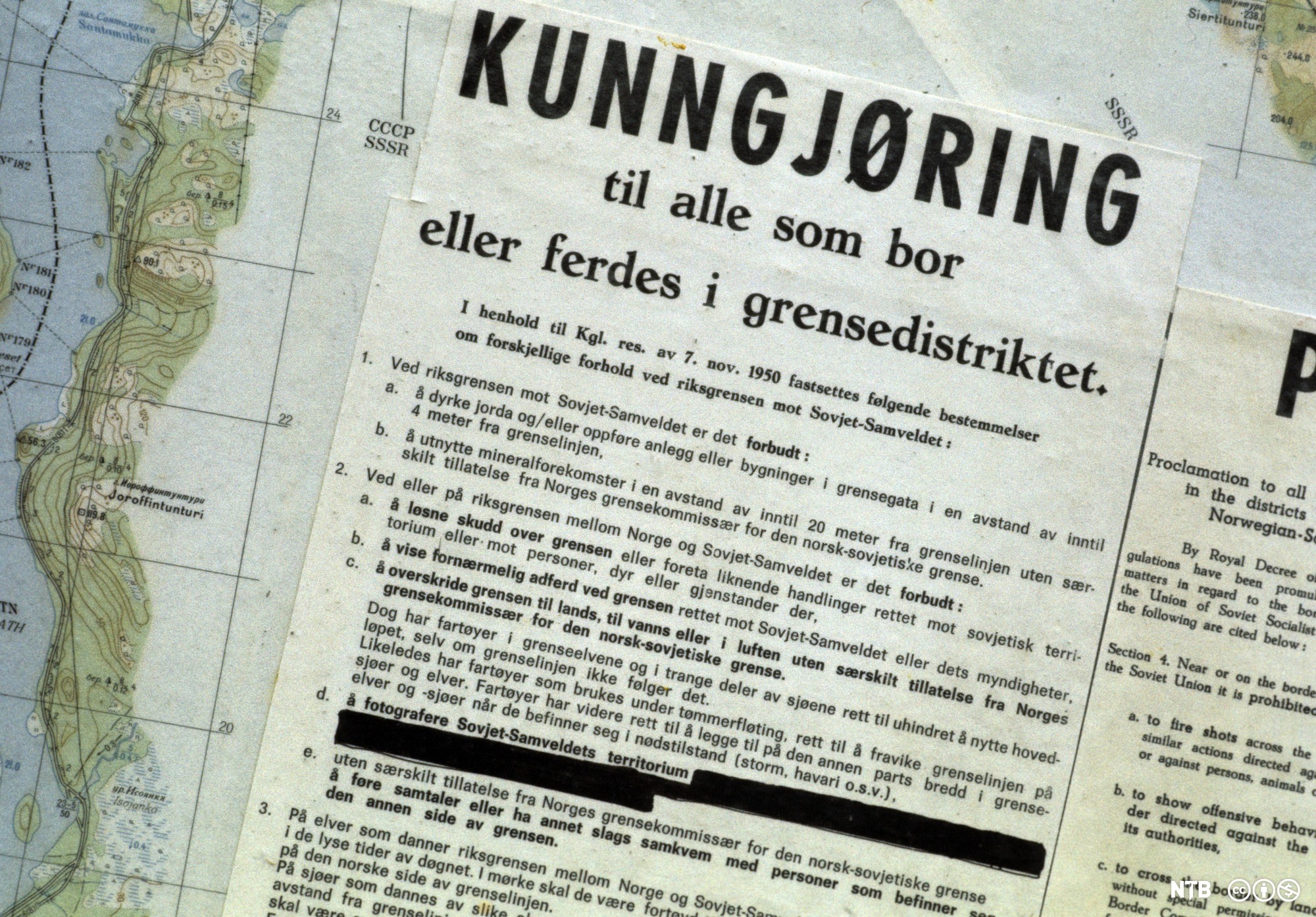På eit kartutsnitt av norskegrensa ligg eit dokument med overskrifta "Kunngjøring til alle som bor eller ferdes i grensedistriktet". Foto.