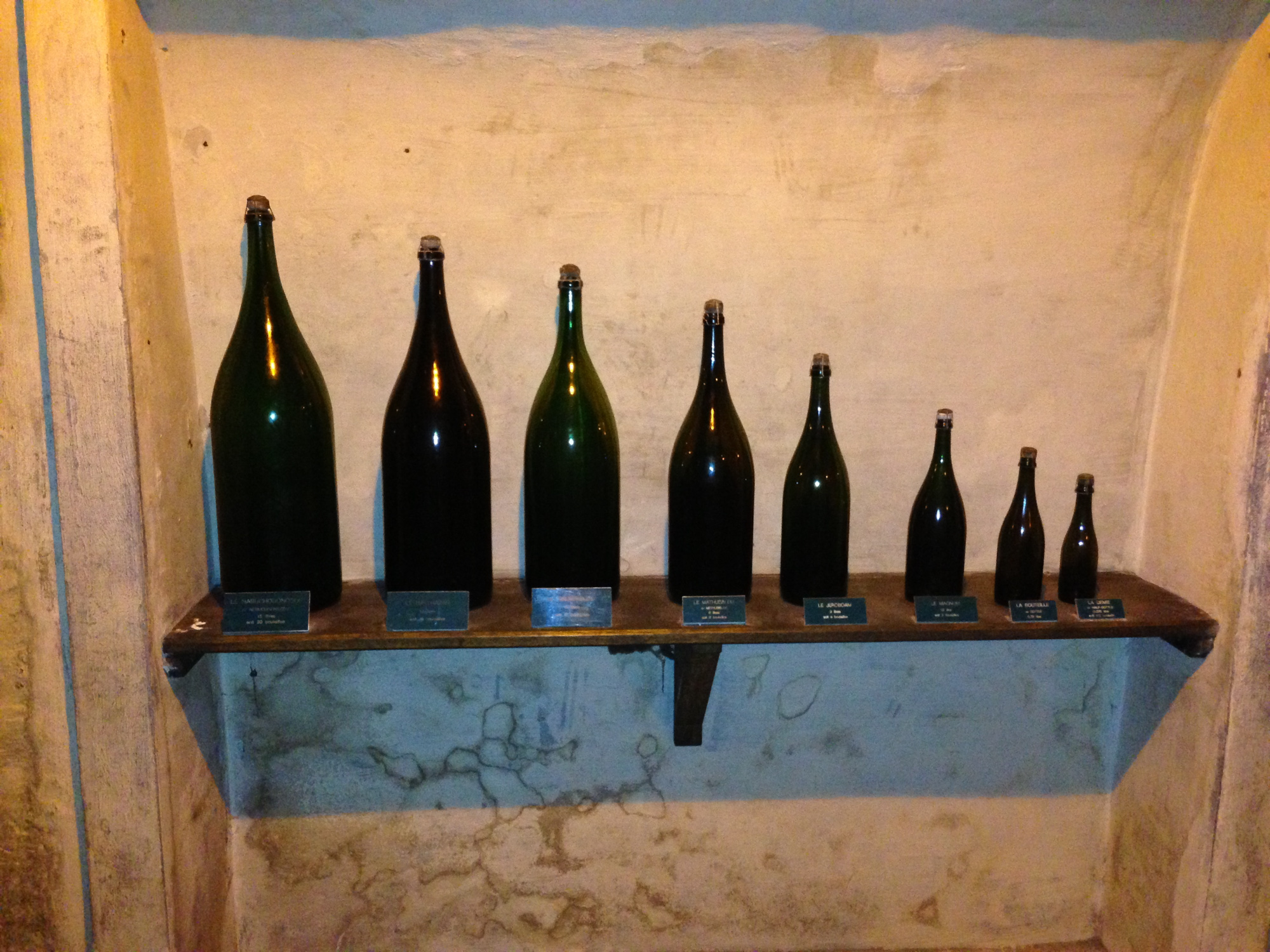 Flasker i ulik størrelse er stilt opp på ei hylle. Foto.