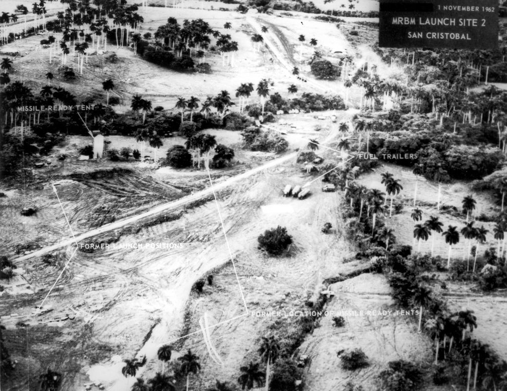 Flyfotoet viser kamuflerte utskytingsramper for missiler. Noen tankbiler står oppstilt på området. Det vokser palmetrær der. Foto.