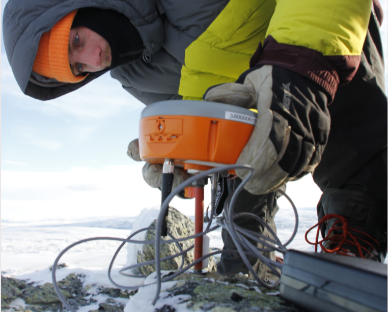 Person som er ute om vinteren og bruker et måleinstrument. Foto.