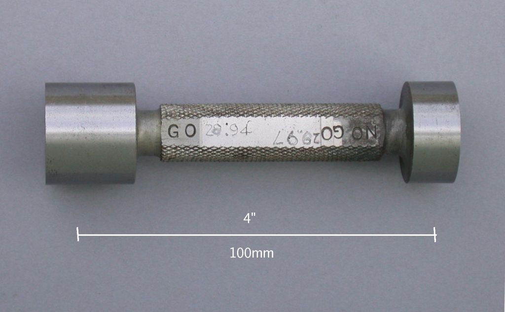 Sylinderformet verktøy med dreide flater på endene og ruglete mønster på midten. Foto.
