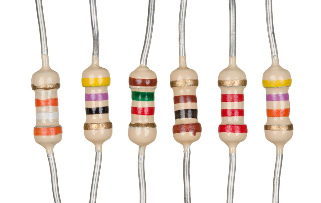 Seks elektroniske komponenter med sylindrisk form og ett tilkoplingsbein i hver ende. Hver enkelt komponent har fargeringer i forskjellige farger. Foto.